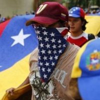 A Venezuelan opposition protester wears a U.S. flag bandanna around his face.