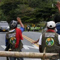 Two men waving at police car. Photo Credit: Juan Pablo Rueda Bustamante / El Tiempo