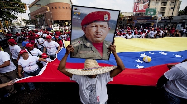 | A man holds a giant portrait of Chavez during a rally in Caracas AP | MR Online