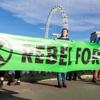 Extinction Rebellion activists hold a banner reading “Rebel for life.” Photo Credit- @ Thomas Katan.