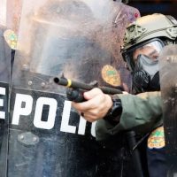 A policeman shoots rubber bullets at protesters throwing rocks and water bottles during a demonstration next to the city of Miami Police Department, Saturday, May 30, 2020, downtown in Miami. Protests were held throughout the country over the death of George Floyd, a black man who died after being restrained by Minneapolis police officers on May 25. (AP Photo/Wilfredo Lee)