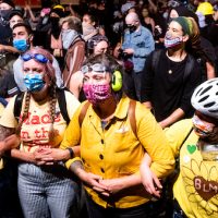 Black Lives Matter protesters gather outside the Mark O. Hatfield United States Courthouse on Sunday, July 19, 2020, in Portland, Ore. Officers used teargas and projectiles to move the crowd after some protesters tore down a fence fronting the courthouse. (AP Photo/Noah Berger)