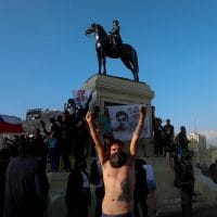 An anti-government protester raises his arms at Plaza Italia on the day Chileans voted in a referendum to decide whether the country should replace its 40-year-old constitution, written during the dictatorship of Gen. Augusto Pinochet, in Santiago, Chile, Oct. 25, 2020. Luis Hidalgo | AP