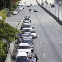 Men stand alongside vehicles lined up to enter a petrol station during a nationwide fuel crunch, in Caracas, Venezuela