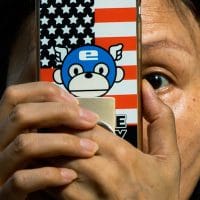 A woman takes a photo with a phone that has a United States flag themed cover outside the United States Consulate in Chengdu in southwest China’s Sichuan province on, July 26, 2020. Ng Han Guan | AP