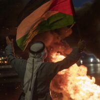 A protester flies a Palestinian flag at Israeli troops during a demonstration in support of Palestinian prisoners in Israeli jails, at the entrance of the occupied West Bank city of Nablus, Monday, September 13, 2021