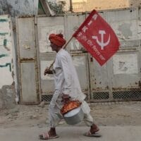 A farmer at the protest encampment at Delhi’s Singhu Border carries the flag of the All India Kisan Sabha, 21 November 2021. Subin Dennis / Tricontinental: Institute for Social Research