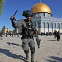 A member of the Israeli security forces attacks worshippers at the Dome of the Rock mosque during clashes at Jerusalem's al-Aqsa Mosque compound, on 15 April 2022 (AFP)