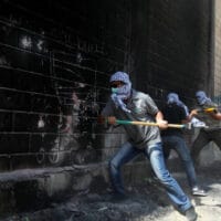 PALESTINIANS YOUTH USE SLEDGE HAMMERS TO KNOCK HOLES THROUGH PART OF A WALL CONNECTED TO ISRAEL’S CONTROVERSIAL SEPARATION BARRIER IN THE ABU DIS NEIGHBORHOOD, BORDERING JERUSALEM ON JULY 9, 2013. PALESTINIANS CALL THE WALL AN “APARTHEID WALL.” PHOTO BY ISSAM RIMAWI (C) APA IMAGES.