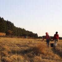 Two young girls return to their homes after drawing water from a stream that the farm dwelling community shares with wild animals, 29 July 2020.