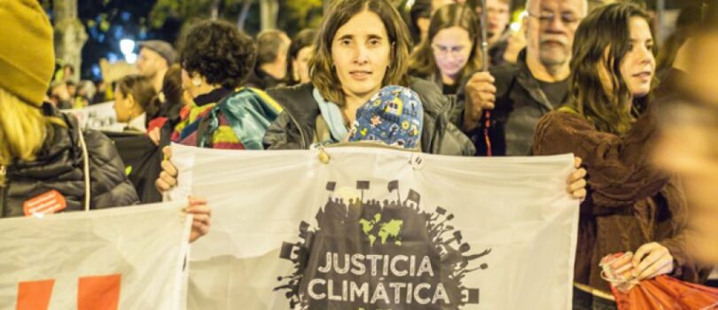 | A protester holds up a sign that reads Climate Justice in Spanish Photo Friend of the Earth | MR Online