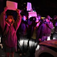 Protesters hold up blank papers and chant slogans as they march in protest in Beijing, Sunday, November 27, 2022