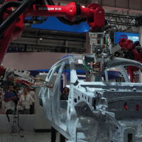 Visitors watch robotic arms assemble a car during the World Robot Conference in Beijing last week