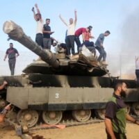 PALESTINIANS TAKE CONTROL OF AN ISRAELI TANK AFTER CROSSING THE BORDER FENCE WITH ISRAEL FROM KHAN YUNIS IN THE SOUTHERN GAZA STRIP ON OCTOBER 7, 2023. (PHOTO: STRINGER/ APA IMAGES)