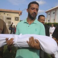 A relative carries the body of Amir Ganan, who was killed by an Israeli air strike, during his funeral in Khan Younis, Gaza Strip, October 10, 2023