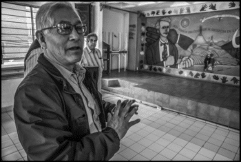 | Benedicto Martínez in the offices of the FAT in Mexico City points to a mural by Mike Alewitz celebrating the binational solidarity partnership between the FAT and the United Electrical Workers David Bacon | MR Online