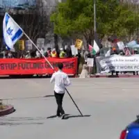 A counter-protester holding an Israeli flag walks into the car park near a protest at Google Cloud offices in Sunnyvale, California on April 16, 2024 [File: Reuters/Nathan Frandino]