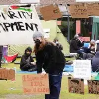 A student adjusts a sign at an encampment on the grounds of Newcastle University, protesting against the war in Gaza, May 2, 2024