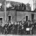 A white-supremacist mob poses in front of the burned-down office of Black-owned newspaper The Daily Record.